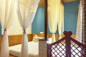A bedroom with a wooden headboard, a bed with white bedding, and a colorful geometric pillow.