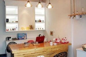 A wooden dining table with a laptop, a red box, and decorative items. There are three pendant lights above the table. - WuzhenThose Years, Those Events, Those People (Tongxiang)
