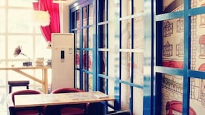 A room with a wooden desk, red chairs, a white cabinet, and a window with blue frames. - WuzhenThose Years, Those Events, Those People (Tongxiang)