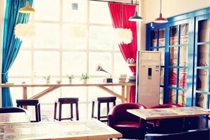 A room with a large window, a table with chairs, a red chair, and a blue cabinet. - WuzhenThose Years, Those Events, Those People (Tongxiang)