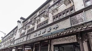 A traditional building with multiple stories, featuring ornate wooden balconies and a tiled roof. - WuzhenThose Years, Those Events, Those People (Tongxiang)