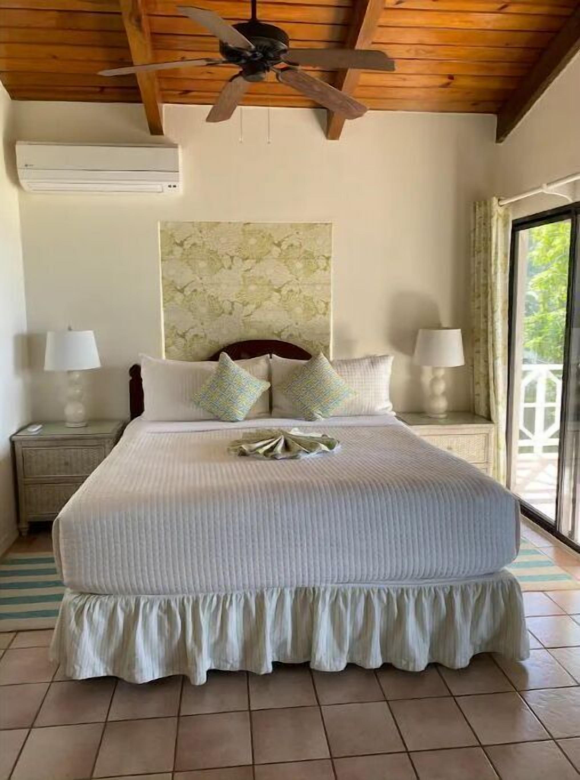 Ein Schlafzimmer mit einem großen Bett, Holzboden und einem Deckenventilator.