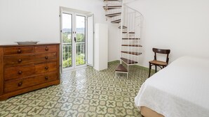 Un dormitorio con escalera espiral, cómoda de madera, una silla y una cama.