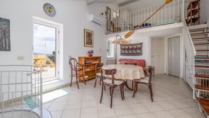 Amplia sala de estar con mesa de comedor, sillas, sofá y escalera.