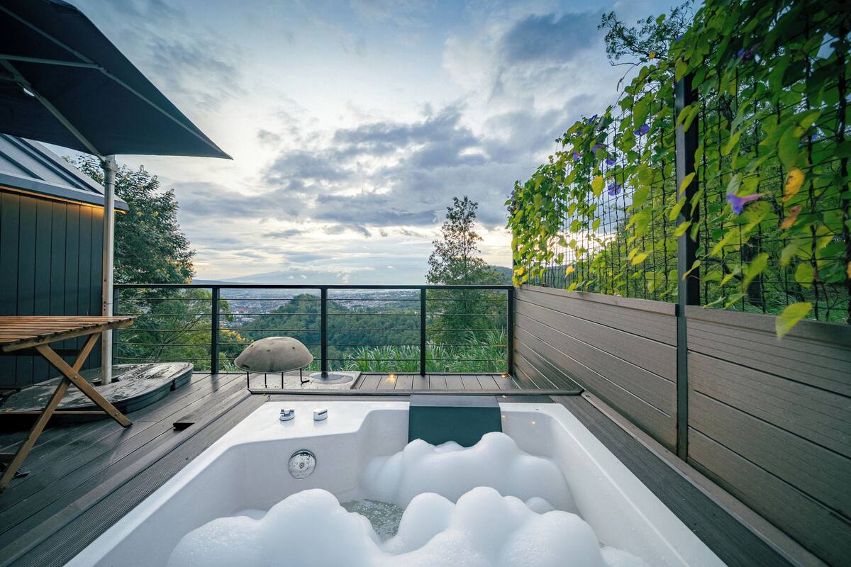 A hot tub on a deck with a view of the landscape.