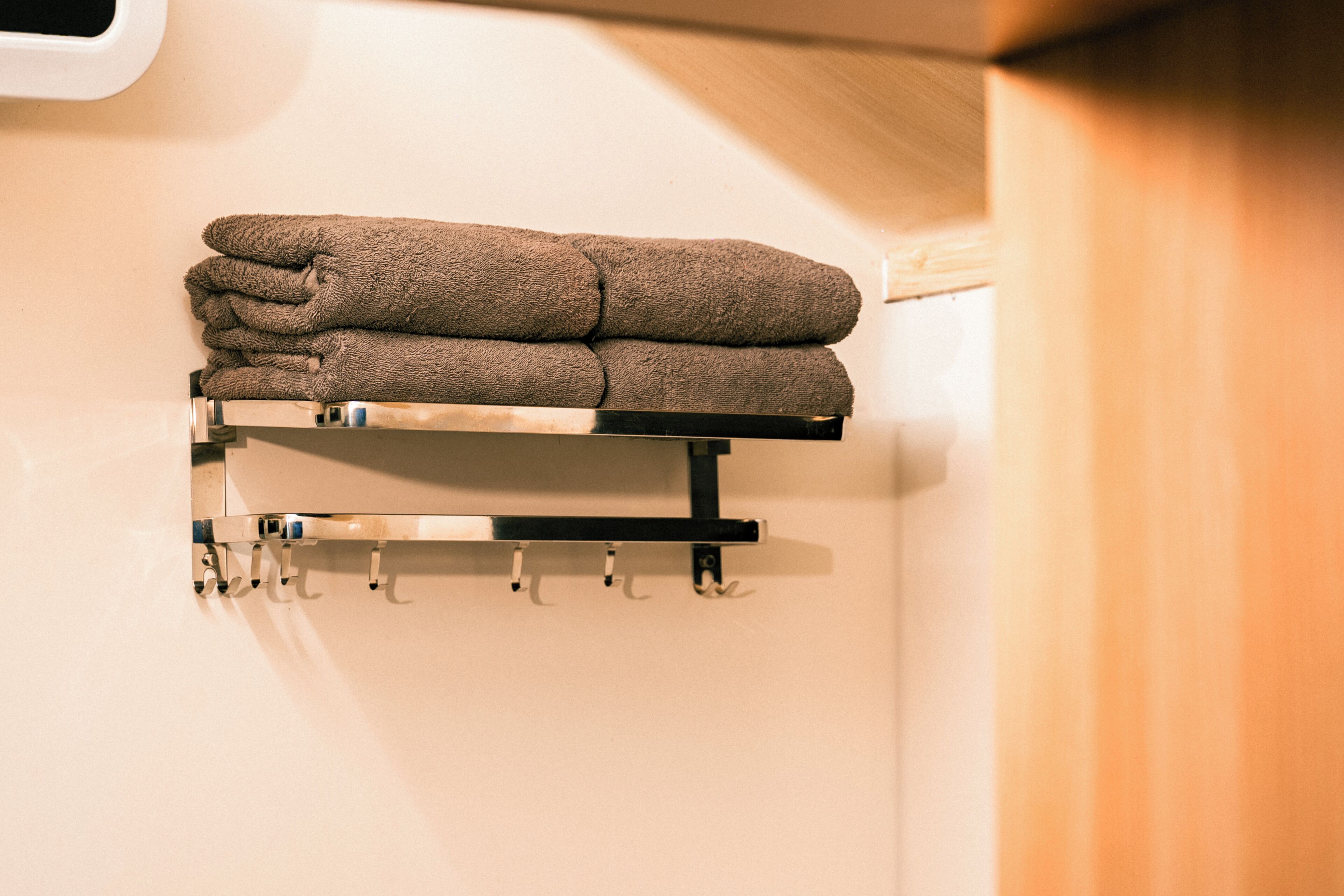 Een handdoekrek met opgevouwen handdoeken en haakjes om spullen aan op te hangen.