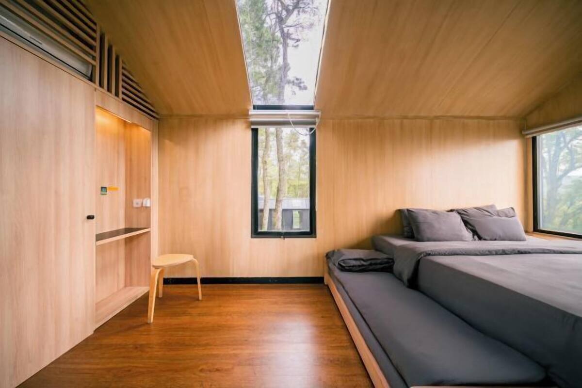 A bedroom with a bed, a window, and a wooden wardrobe.