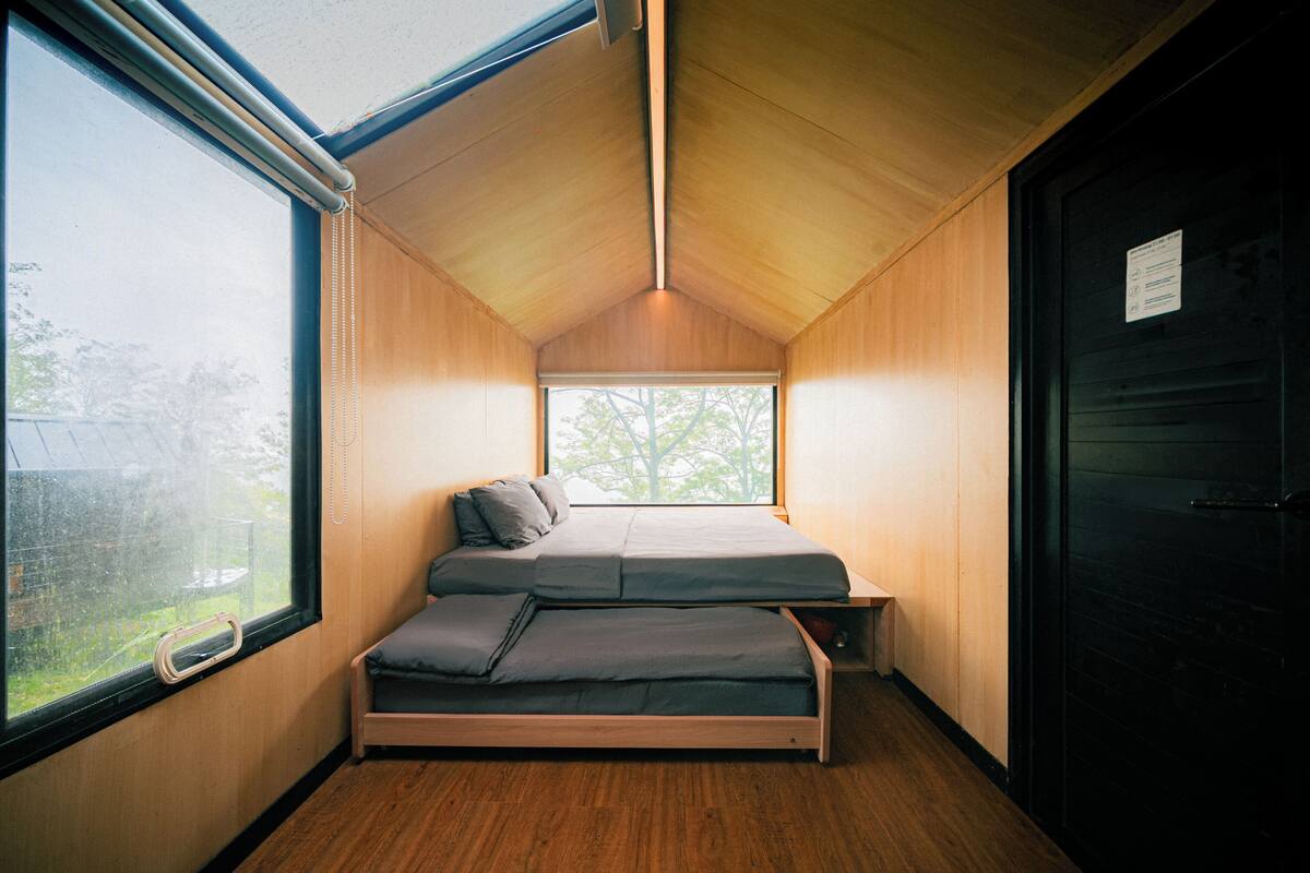 A compact room with a bed, a window, and a door.