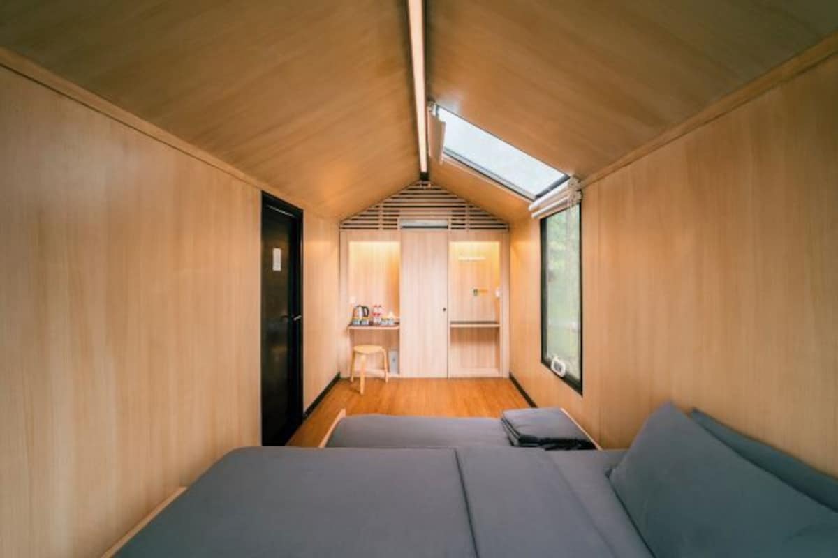 A compact room with a bed, a desk, and a skylight.