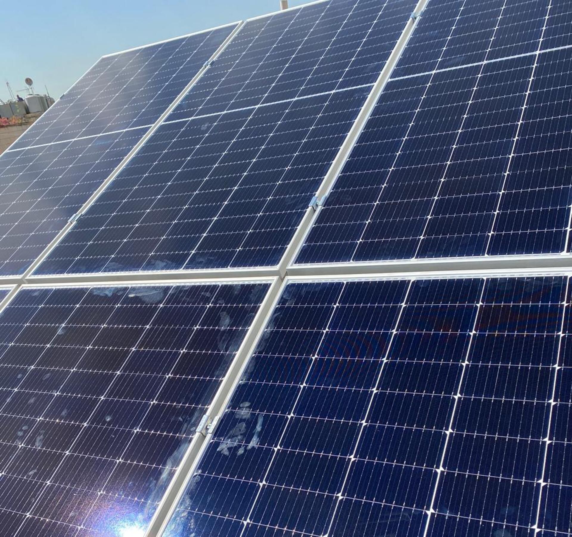 A close-up of solar panels with a clear sky in the background.