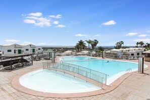 A swimming pool with a curved edge, surrounded by a tiled deck and a railing.
