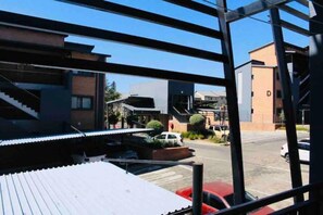 A modern building with a metal framework, a parking lot with cars, and a clear blue sky. - Eazy Inn by Mall of Africa (Midrand)