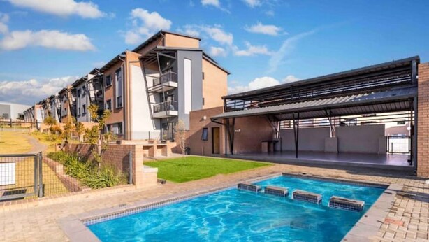Ein modernes Mehrfamilienhaus mit Schwimmbad, Außenbereich zum Sitzen und einer überdachten Terrasse.
