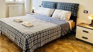 A bedroom with a bed, a nightstand, a lamp, and a window. - one bedroom apartment with parking, 5 minutes walk from piazzale Arnaldo (Brescia)