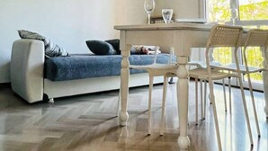 A modern living room with a sofa, dining table, chairs, and a unique black pendant light. - one bedroom apartment with parking, 5 minutes walk from piazzale Arnaldo (Brescia)