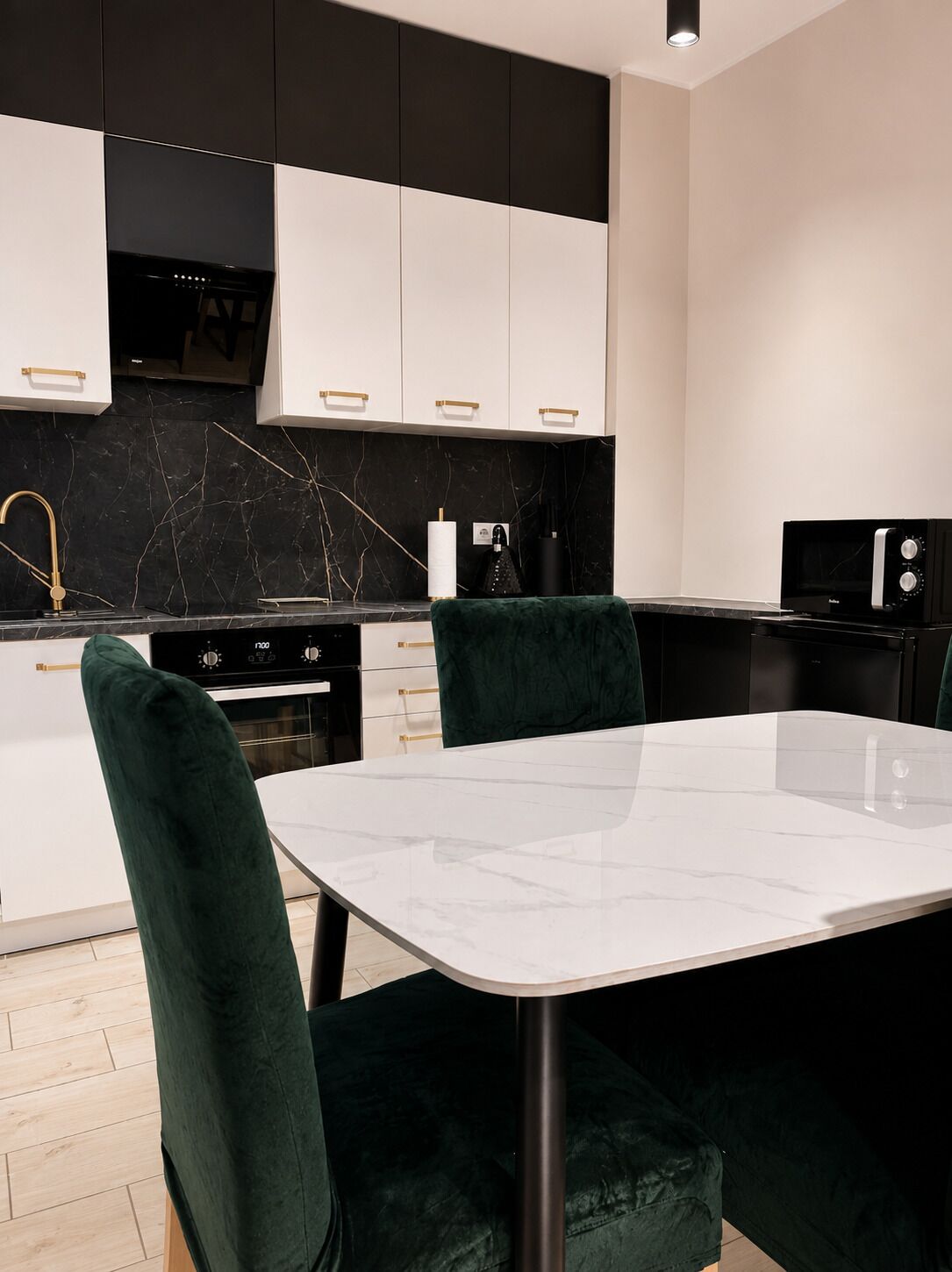 A modern kitchen with white cabinets, a black backsplash, and a marble countertop.