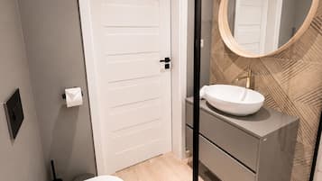 A modern bathroom with a toilet, sink, and shower.