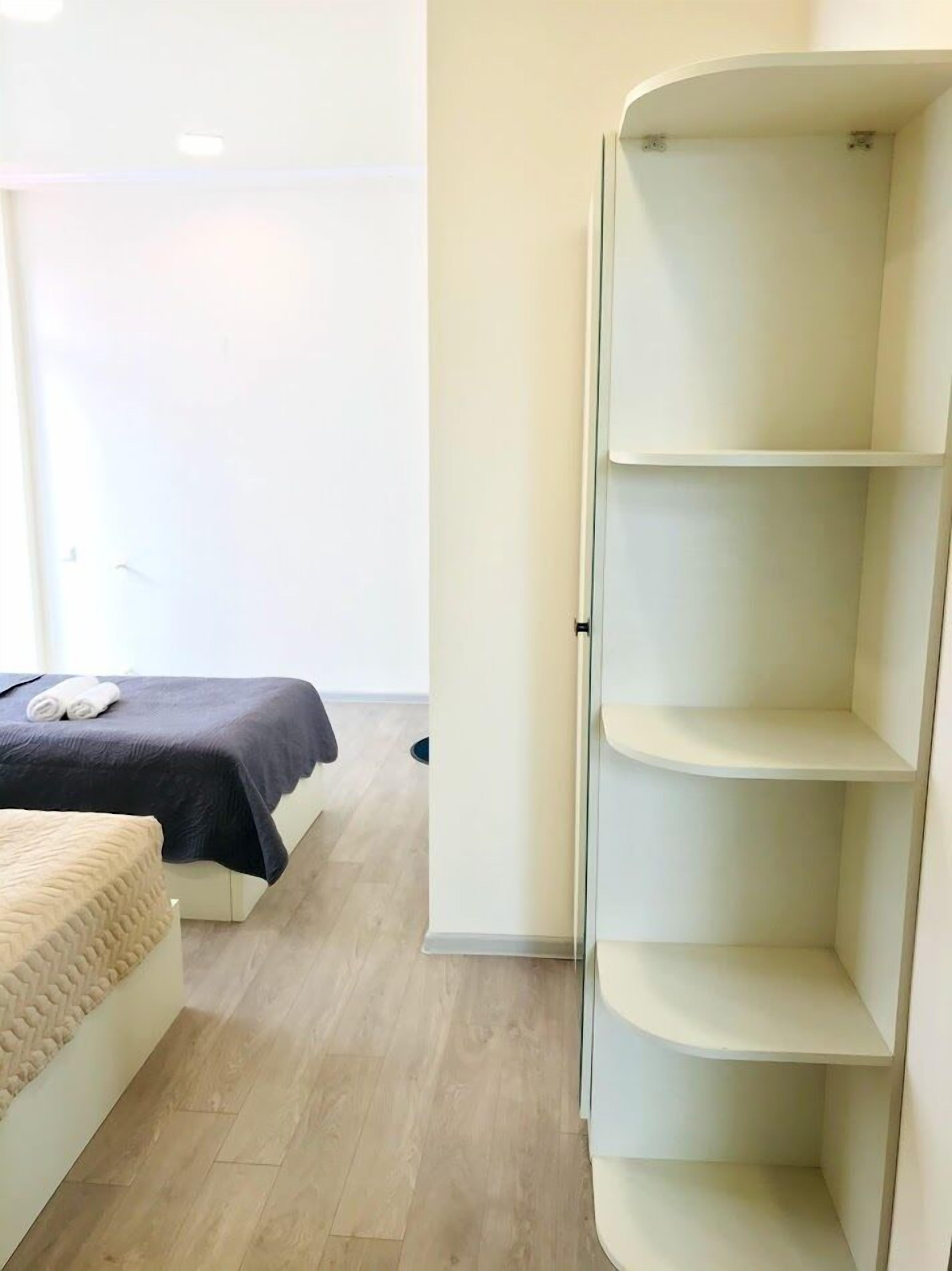 Un dormitorio con cama, una mesita de noche y estanterías empotradas.