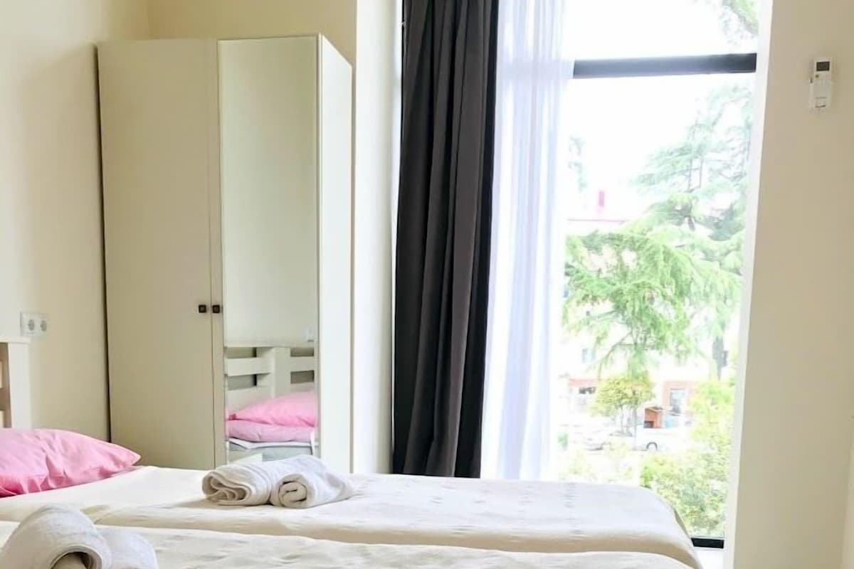 A hotel room with a bed, a wardrobe, and a window with curtains.