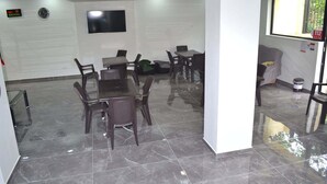 A conference room with a glass table, dark chairs, a TV on the wall, and a window with a number sign. - Hotel Gurya (Kobuleti)