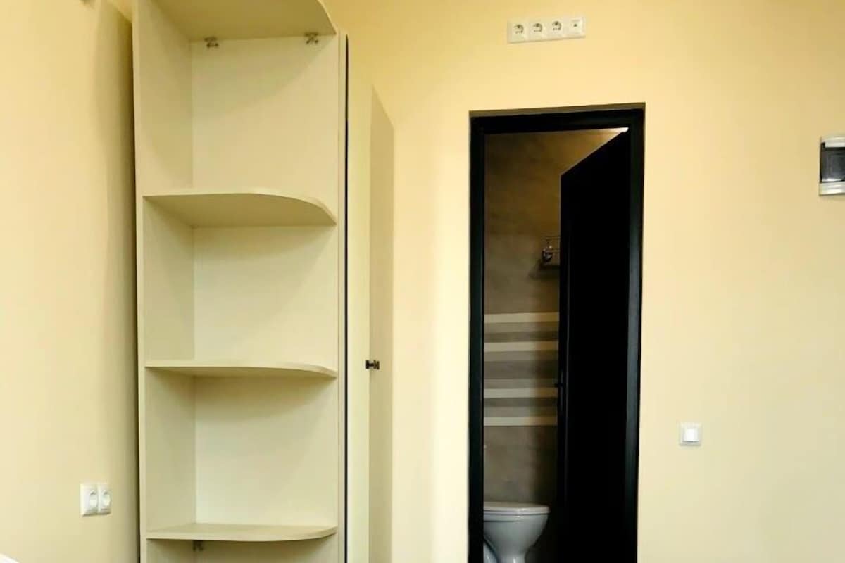 A hotel room with a bed, a towel, a wardrobe, and a bathroom door.