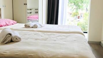 Cama bem arrumada com toalhas dobradas, um guarda-roupa e uma janela com cortinas.