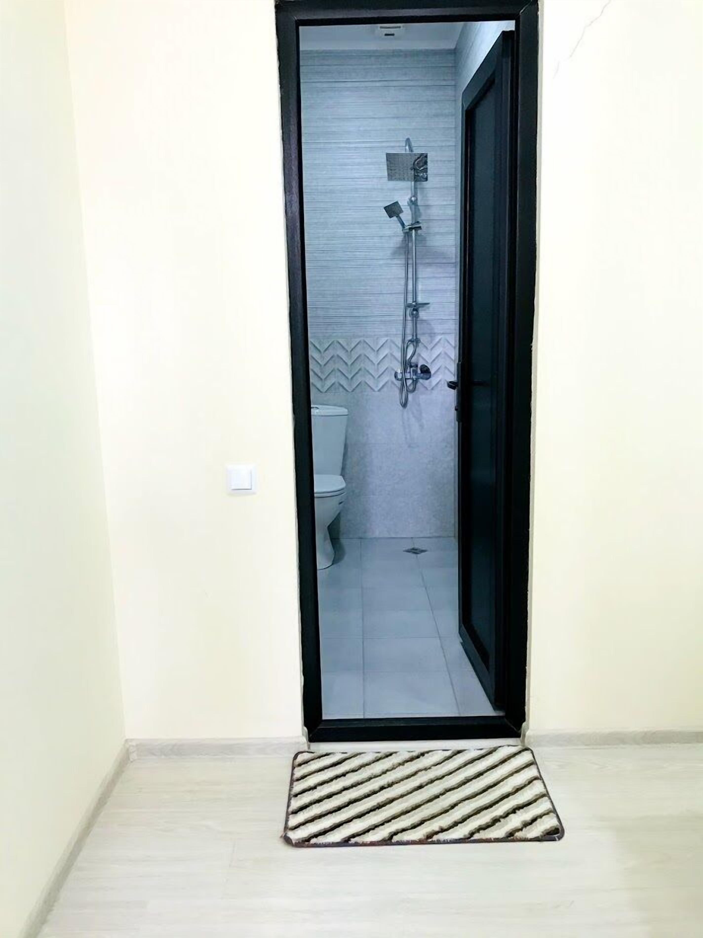 Un baño con ducha, inodoro y paredes de azulejos.