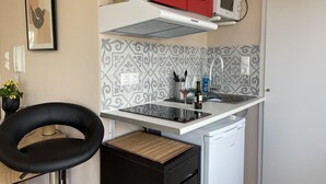 A compact kitchen with a microwave, a red cabinet, and a patterned backsplash. - Cozy Apartment in Heart Athens Near Metro Fix 100m (Athens)