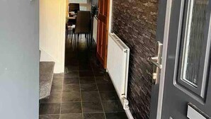 A hallway with a dark textured wall, a door with a glass panel, and a tiled floor. - Spacious 3-bed House in Swindon (Swindon)