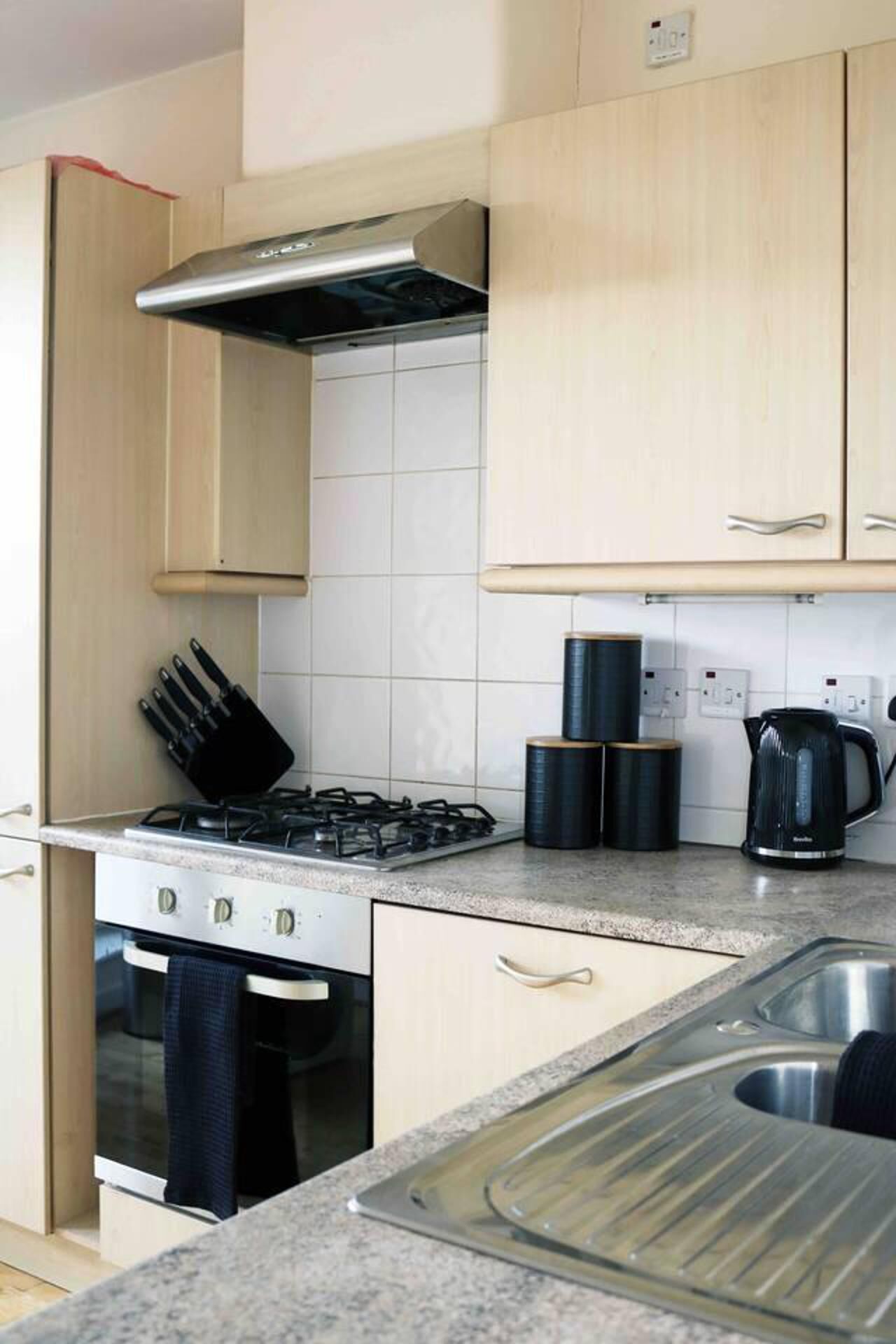 A compact kitchen with a gas stove, oven, and a stainless steel sink.