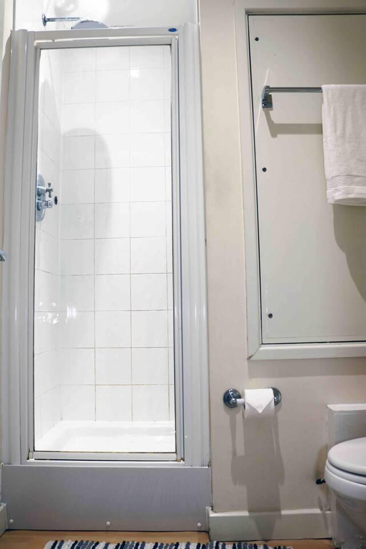 Un baño con ducha, inodoro y toallero.