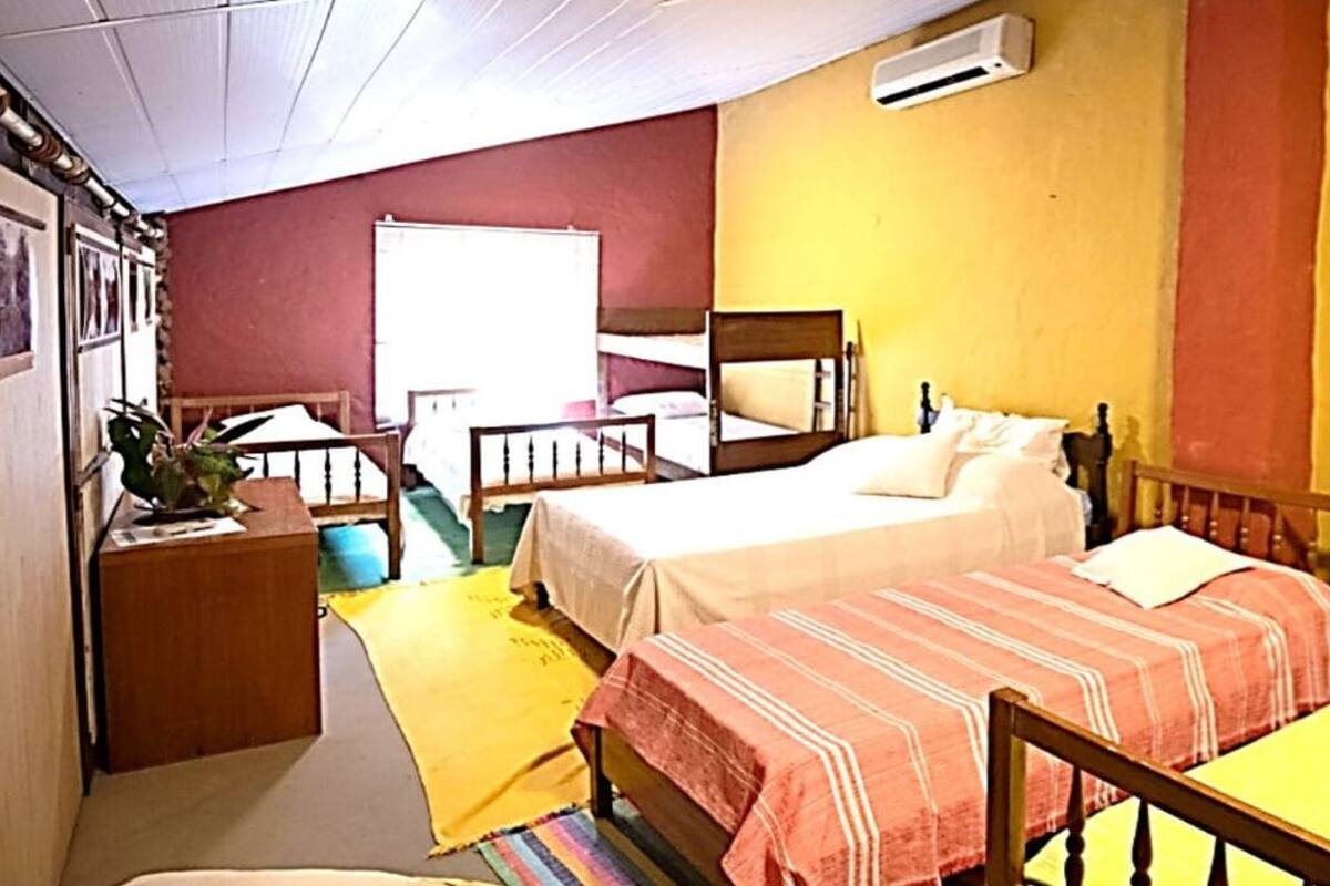 A small, cozy room with two single beds, a wooden table, a small desk, and a window.