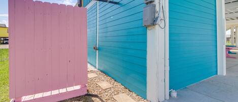 A house with a teal exterior, a pink fence, and a visible garage door.