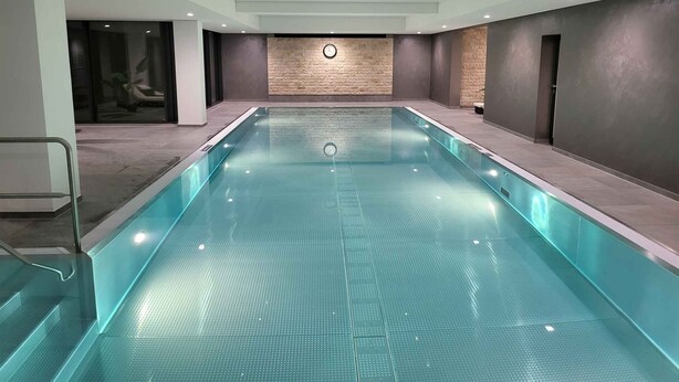 Uma grande piscina interna com piso revestido e um relógio na parede.
