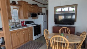A compact kitchen with wooden cabinets, a microwave, stove, refrigerator, and a dining area with wooden chairs and a table. - Quiet Get away Lot #2 fisherman, family, Pet friendly, boat ramp, dock, Beaches (Port Clinton)