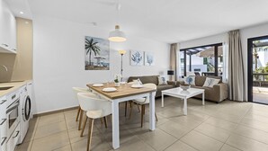 Un soggiorno moderno con zona pranzo, divano e cucina completa di lavatrice.