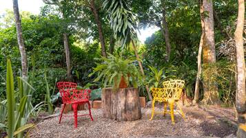 Deux chaises à ossature métallique et un tronc d’arbre servant de siège, le tout dans un jardin.
