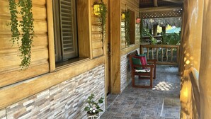 Un porche cubierto de madera con suelo de baldosas de piedra, paredes de madera y un área de estar con una mesa y sillas.