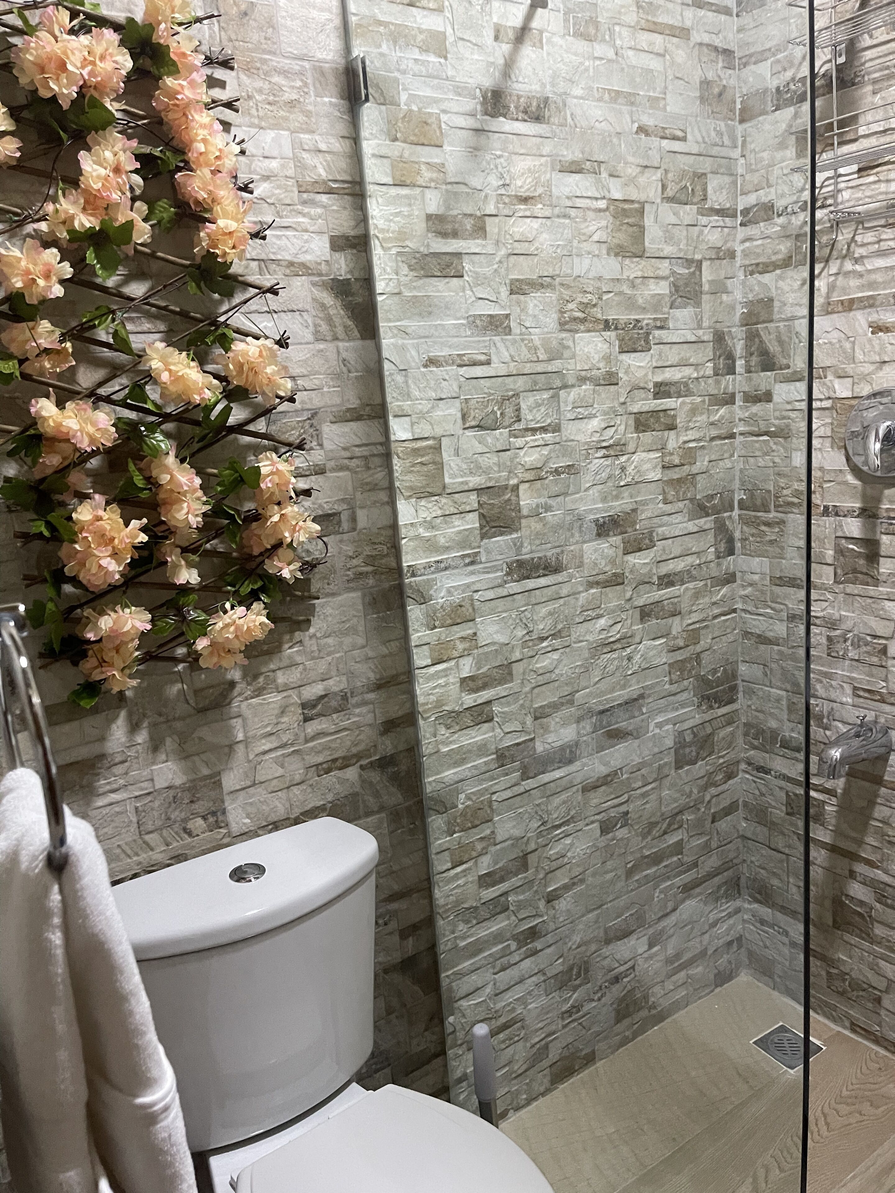 Un bagno con parete in pietra, un WC e zona doccia.