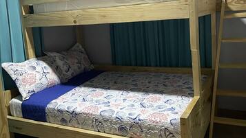 Ein Holzbett mit Etagen, einer gemusterten Bettdecke, zwei Kissen und einer blauen Decke.