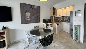 A modern kitchen with white cabinets, a microwave, and a refrigerator. - Bright 31m2, flowered terrace, near Croisette (Cannes)