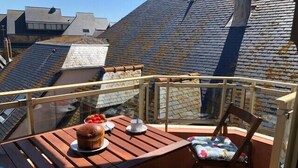 Una terraza de madera con una mesa, una silla, un cuenco de fresas y una taza de café.