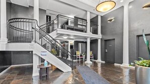 A spacious lobby with a grand staircase, a reception desk, and a large potted plant. - Emerald City Pentouse (Seattle)