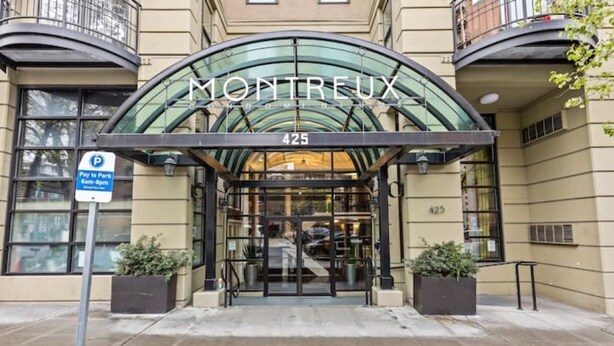 The entrance of a hotel with a glass facade and a curved roof structure. - Emerald City Pentouse (Seattle)