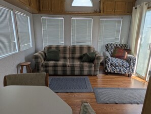 A cozy living room with a plaid sofa, patterned armchair, and a small wooden stool.