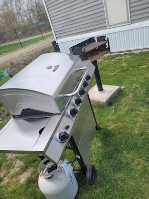 A portable gas grill with four burners, a side shelf, and a gas tank. - Clean get away fishing, birding, close to beach, restaurants, dock, boat ramp (Port Clinton)