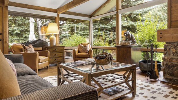 Una sala de estar acogedora con chimenea, asientos cómodos y ventanas amplias que ofrecen vistas al exterior.