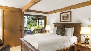 Un dormitorio con una cama grande, cabecera de madera y una ventana con vista a muebles de exterior.
