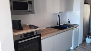 Cocina compacta con microondas, horno, lavavajillas y fregadero.