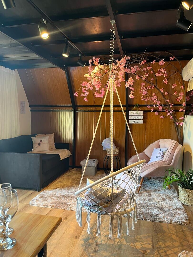 Una sala acogedora con un sillón colgante, un sofá y piso de madera.